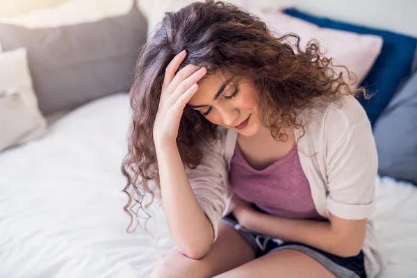 woman sitting in bed bent over in pain 