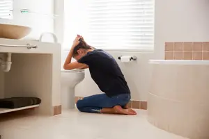 woman with morning sickness bent over the toilet
