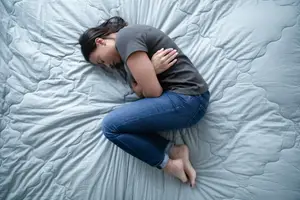 woman with endometriosis pain in fetal position on her bed