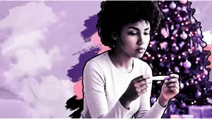 woman looking at negative pregnancy test with christmas tree in the background
