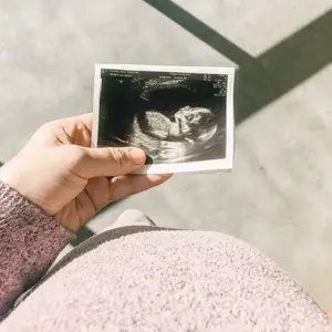 pregnant woman staring down at her ultrasound image
