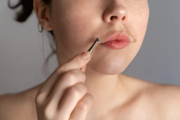 woman plucking her facial hair due to pcos