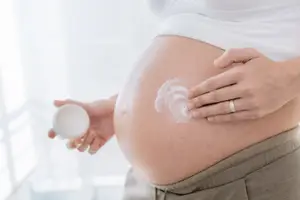 woman moisturizing her pregnant belly