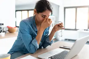 mentally exhausted woman hunched over her computer
