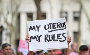 reproductive rights activist holding a sign that reads "my uterus my rules"