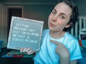 infertility warrior arden cartrette holding a sign that reads "getting pregnant is easy for everyone, neither is staying pregnant"