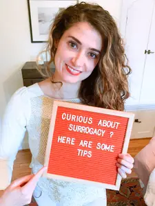 maryjane carnahan holding a sign that reads "curious about pregnancy? here are some tips"